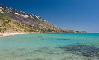 a breathtaking view of a mountainous landscape with a clear blue sea and clear white sand at Lygies Studios