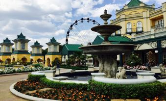 An amusement park features a large fountain surrounded by buildings and flowers in the plaza at Anew Hotel Parktonian Johannesburg