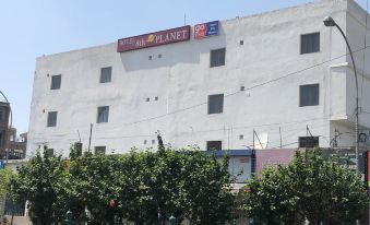 "a white building with a red sign that reads "" william planet "" is surrounded by trees and bushes" at Hotel 8th Planet