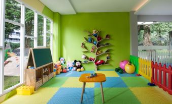 a green room with various toys , including a chalkboard , a tree , and a small table at Royal Ambarrukmo Yogyakarta