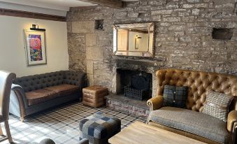 a cozy living room with a stone fireplace , two couches , and a coffee table , creating a warm and inviting atmosphere at The Greyhound Hotel