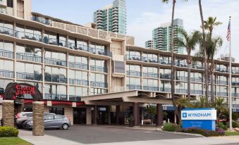 a hotel building with multiple cars parked in front , and the wyndham hotel sign visible in the foreground at Wyndham San Diego Bayside