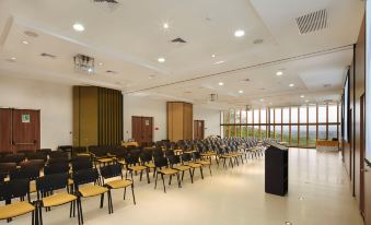 a large , empty conference room with rows of black chairs and wooden paneling on the walls at Hotel Waya Guajira