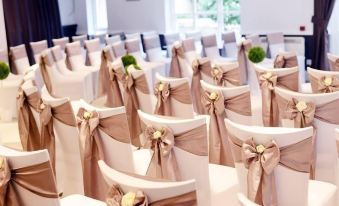 a well - arranged wedding ceremony with rows of chairs covered in white paper and adorned with gold ribbons at Dartmoor Lodge Hotel