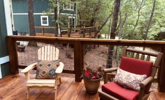 a wooden deck with two adirondack chairs , one on the left and the other on the right side of the deck at Lake Rabun Hotel