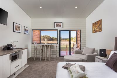 a modern bedroom with a bed , couch , and sliding glass doors leading to a balcony at The Swan Valley Retreat