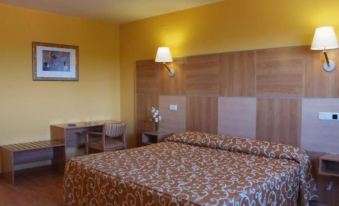 a large bed with a floral comforter is in the middle of a room with wooden walls and a desk at La Cañada