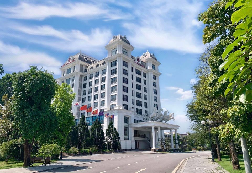 a large white hotel building surrounded by trees and grass , with a road in front of it at Westlake Hotel & Resort Vinh Phuc