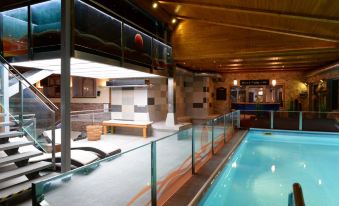 an indoor swimming pool with a glass railing , surrounded by a wooden interior and walls at Hotel Berg