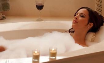 a woman is relaxing in a bathtub filled with bubbles , enjoying a glass of wine at Vandiver Inn