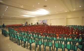 a large auditorium with rows of red chairs and a stage at the front , ready for a meeting or event at Laut Biru Resort Hotel