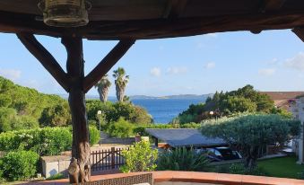 a wooden gazebo overlooks a beautiful view of the ocean and mountains from a balcony at Villa Rosè