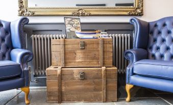 a wooden chest with a picture frame and a blue chair in front of a radiator at The Ship Inn