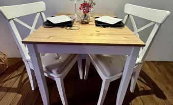 a small dining table with a white chair and two black chairs , surrounded by a wooden floor at Lovely