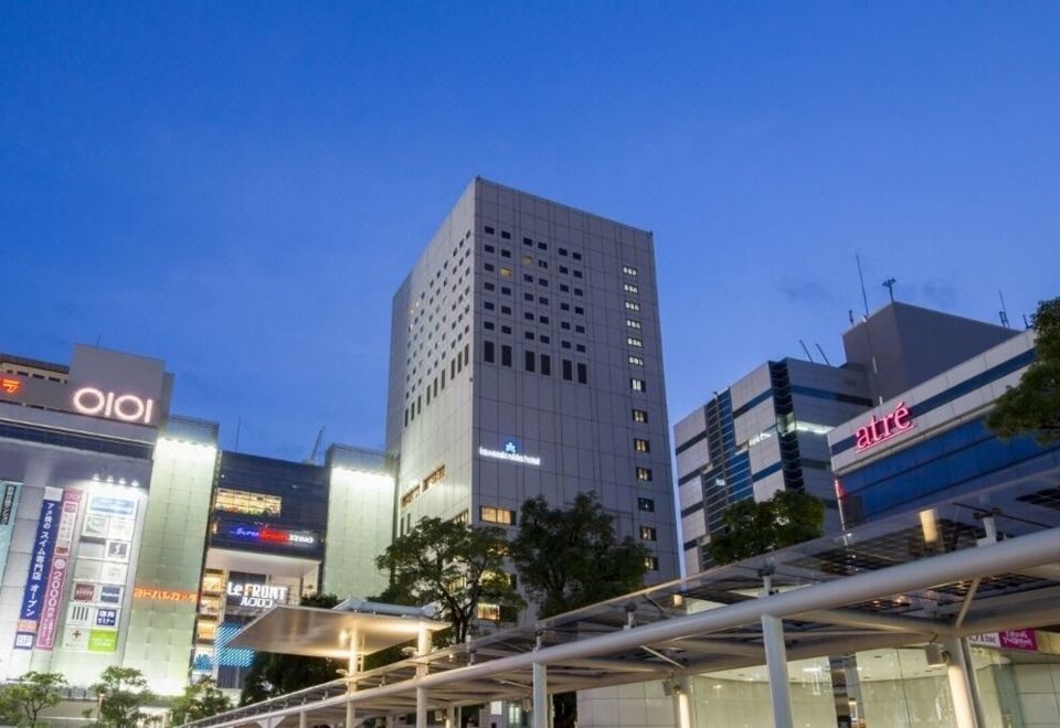 a city street with a tall building on the left side and a shopping mall on the right side at Kawasaki Nikko Hotel