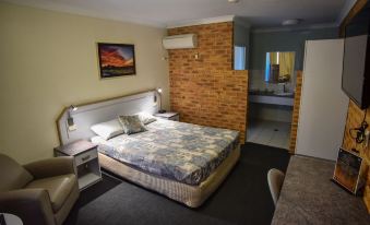a bedroom with a large bed , brick wall , and an air conditioner , along with a living room area at The Crossing Motel