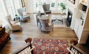 a spacious living room with hardwood floors , two chairs , a fireplace , and a rug on the floor at Briar Barn Inn