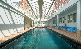 an indoor swimming pool surrounded by a wooden deck , with several lounge chairs placed around it at Manor House Hotel & Spa, Alsager