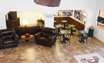 a living room with a brown leather couch , coffee table , and chairs in the middle of the room at Ticaboo Lodge