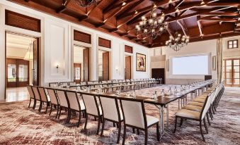 a large conference room with a long table , chairs , and a projector screen , set up for a meeting or presentation at Cap Vermell Grand Hotel