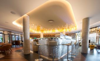 a modern bar with a marble counter and stools , featuring a curved ceiling with lights at Best Western Premier Hotel de la Paix