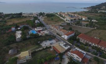 aerial view of a small town near the ocean , with a large group of people gathered on a grassy field at Thetis