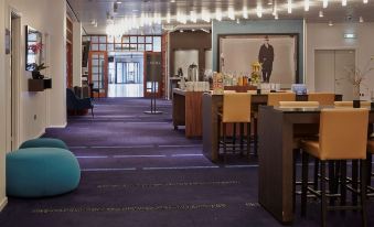 a large , well - lit room with purple carpeting and various seating options , including bean bags and wooden chairs at Radisson Blu Scandinavia Hotel, Aarhus