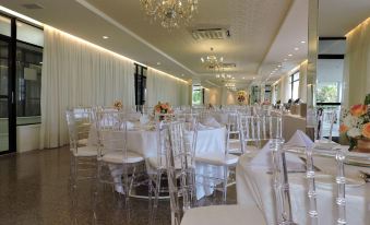 a large banquet hall filled with white chairs and tables , ready for a formal event at Marina Park