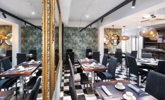 a modern restaurant interior with black and white checkered flooring , gold accents , and black chairs at Salles Hotel Aeroport de Girona