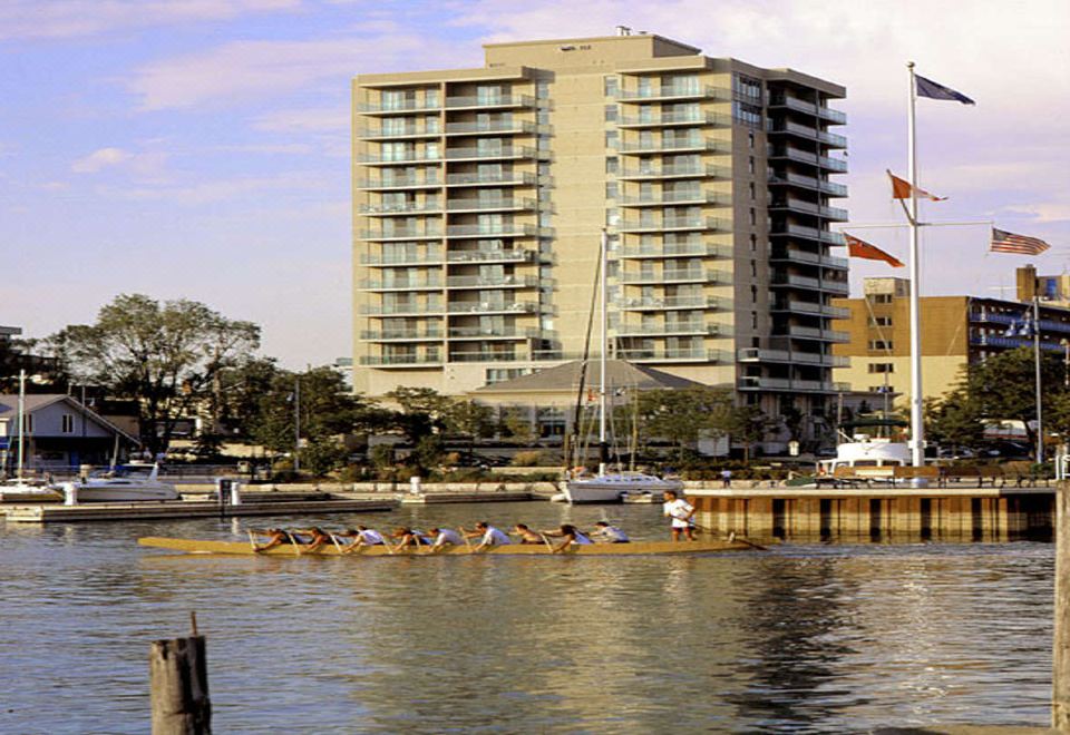a large building with many windows is reflected in the water near a dock where people are kayaking at The Waterside Inn