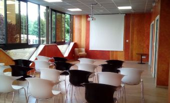 a classroom with rows of chairs arranged in front of a whiteboard , ready for a presentation at Le Grand Hotel