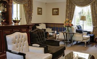 a living room with a couch , chairs , and a dining table set up for a group of people at Risley Hall Hotel