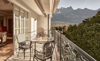 a balcony overlooking a mountainous landscape , with a table and chairs set up for outdoor dining at Grand Resort Bad Ragaz