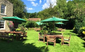 a lush green lawn with several wooden chairs and tables , providing a pleasant outdoor dining area at The Coachman Inn
