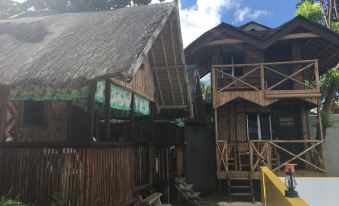 a traditional house with a thatched roof and a balcony is nestled in a tropical setting at The Beachhouse