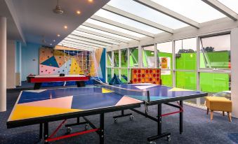 a colorful indoor ping pong table is set up in a room with a mural on the wall at Kingston Hotel Motel