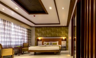 a large bed with a wooden headboard is in the middle of a room with white walls and a window at The Fern Residency Vijayapura