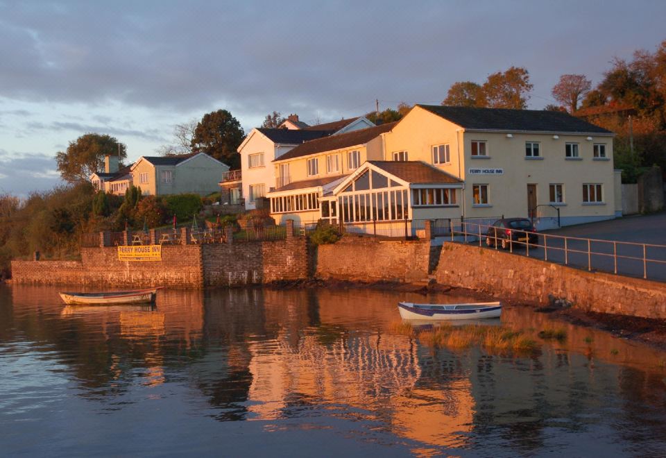 a picturesque town with white houses and boats docked along the waterfront , set against a cloudy sky at Ferry House Inn