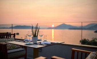 a table set for a meal on a patio overlooking a body of water at sunset at Maestral Resort & Casino