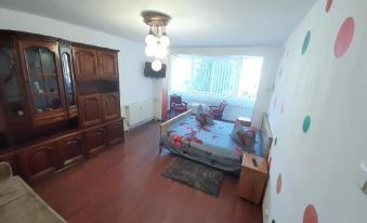 a large bed with a white comforter and orange pillows is in the middle of a room with a couch , table , and window at Marcy Lux