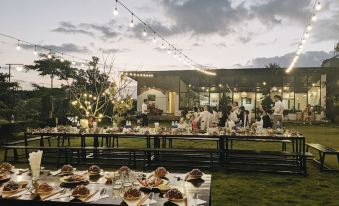 a group of people gathered in an outdoor setting , enjoying a meal and socializing under string lights at XOM Organic Farm Stay