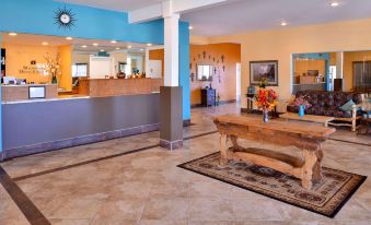 a hotel lobby with a wooden reception desk and a large rug on the floor at The Classic Desert Aire Hotel