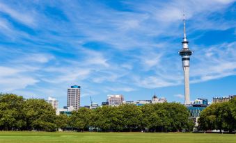 a city skyline with a tall building and a green park in the foreground , under a blue sky with clouds at Knights Inn