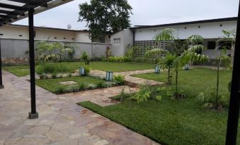 a well - maintained garden with green grass , trees , and a path leading to a house in the background at Urban Lodge