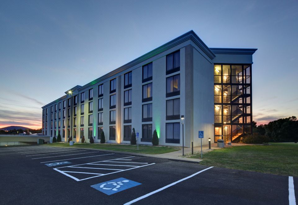 a modern building with a green roof and large windows , surrounded by trees and a parking lot at Holiday Inn Staunton Conference Center