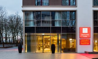 a modern building with large glass windows and people walking in front of it , under an overcast sky at Leonardo Offenbach Frankfurt