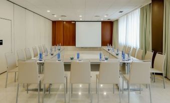 a conference room with a large table surrounded by chairs , and a projector screen on the wall at Hesperia Barcelona Sant Just