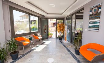 a modern living room with orange chairs , a gray couch , and a glass door leading to an outdoor area at M Suite