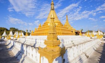 a golden stupa surrounded by white walls and a clear blue sky , with the sun setting in the background at The Home Hotel