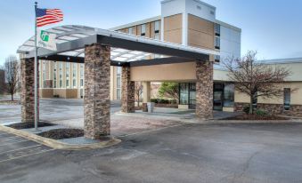 a modern , white - walled building with stone arches and an american flag , under a clear blue sky at Best Western Plus Strongsville Cleveland